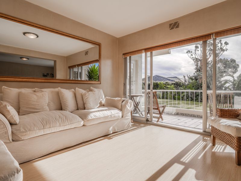 Bright living room featuring laminate flooring and large sliding glass doors that open onto a private balcony with garden views.