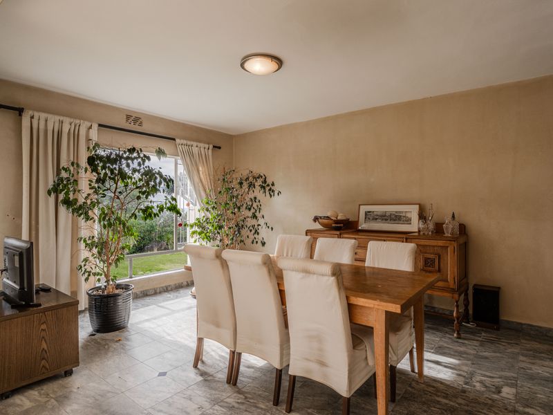 A dining room featuring tiled flooring, a large window providing natural light, and neutral wall finishes.