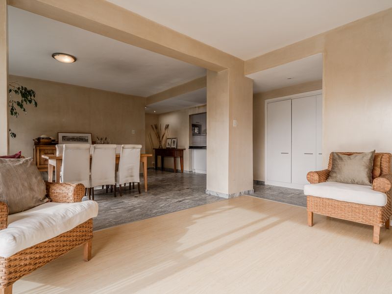 Spacious open-plan living and dining area featuring a mix of laminate and tiled flooring, neutral wall finishes, and built-in storage cupboards.