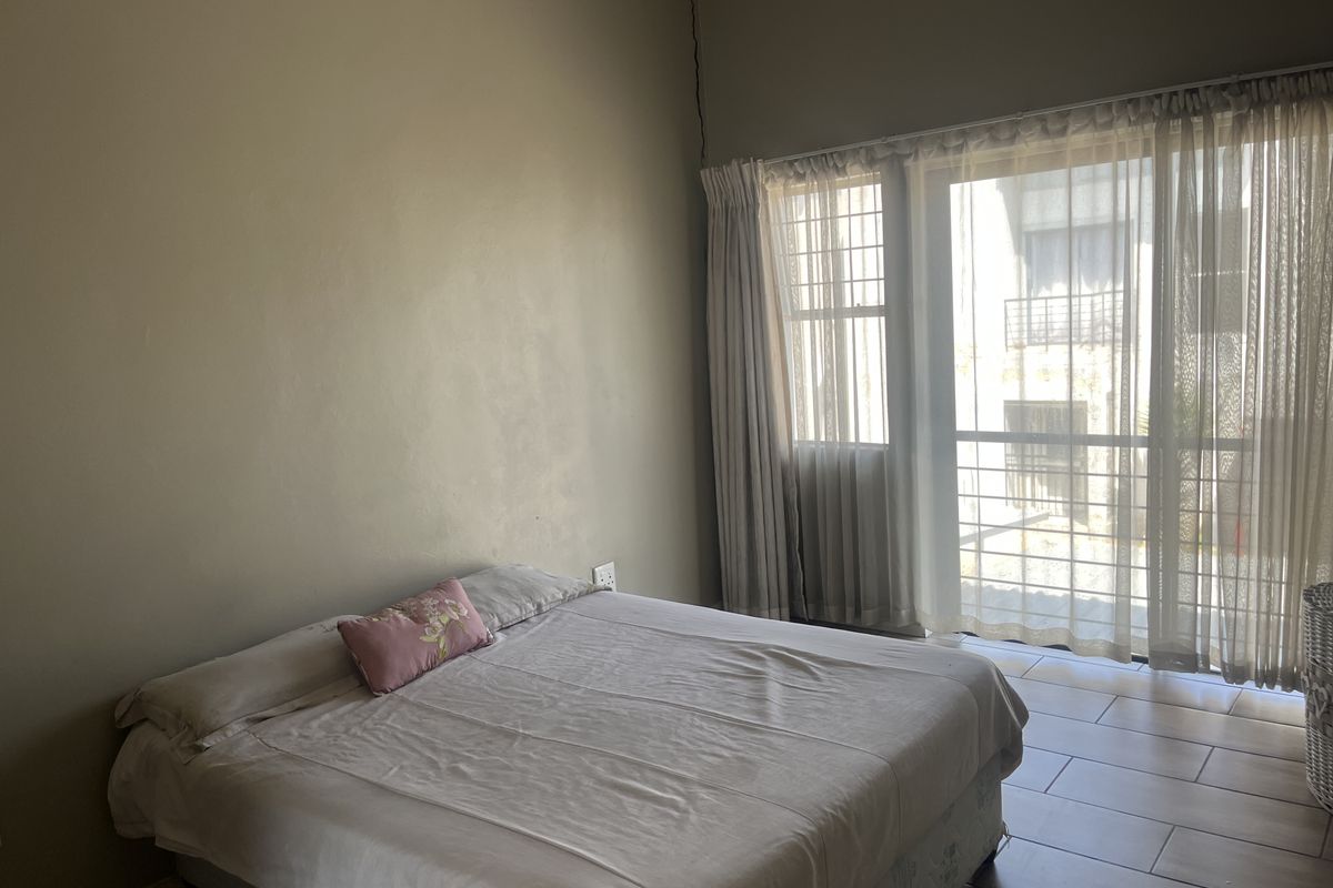 A bedroom featuring tiled flooring and a sliding glass door with security gate, providing access to the exterior.