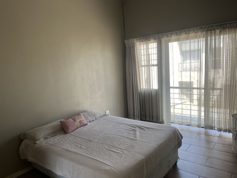 A bedroom featuring tiled flooring and a sliding glass door with security gate, providing access to the exterior.