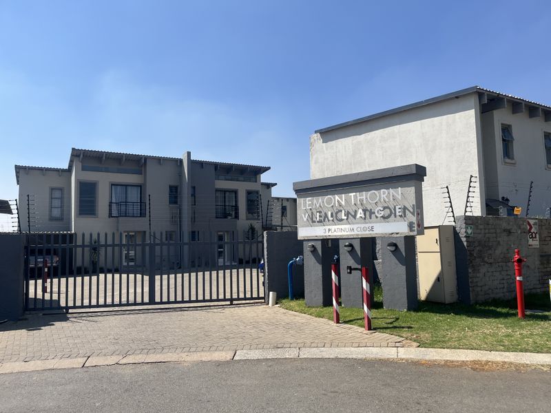 Front entrance view of the Lemon Thorn complex featuring a paved driveway, secure metal gate, and perimeter electric fencing.