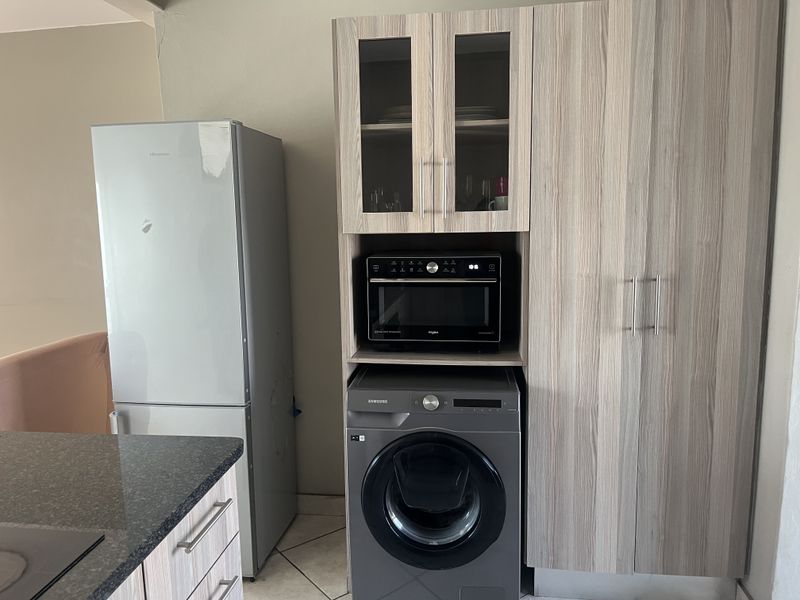 Kitchen area featuring built-in cabinetry with integrated microwave space, granite countertops, and tiled flooring, providing functional storage and workspace.