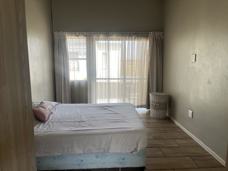 A bedroom featuring tiled flooring and a sliding glass door with access to an outdoor area, providing natural light.