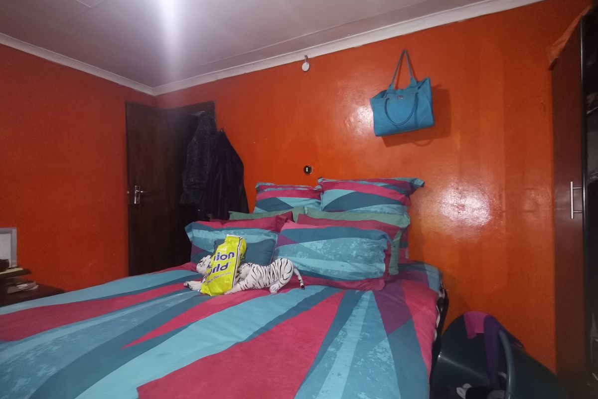 A bedroom featuring orange painted walls and a built-in wardrobe, requiring cosmetic updates to modernize the space.