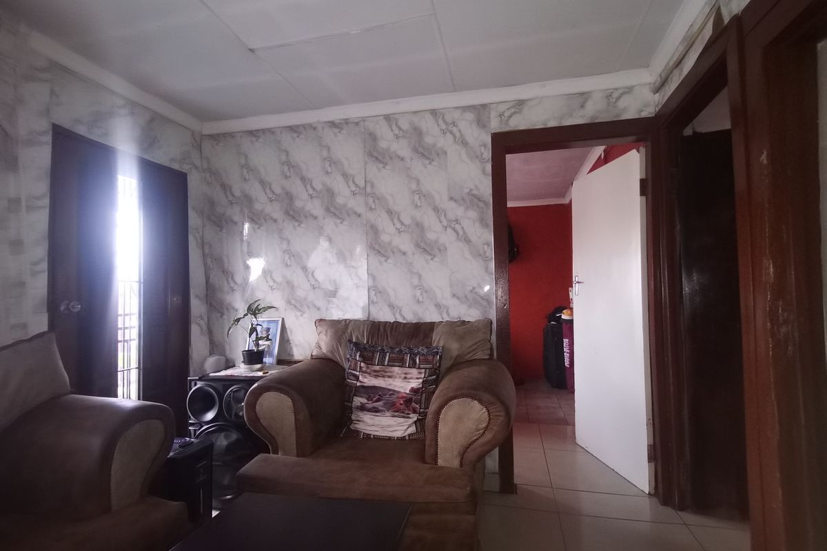 A living room area featuring tiled flooring and marble-effect wall finishes, requiring cosmetic updates to improve the overall aesthetic and condition.