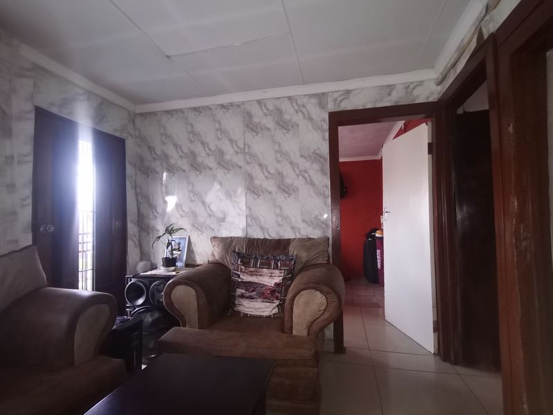 A living room area featuring tiled flooring and marble-effect wall finishes, requiring cosmetic updates to improve the overall aesthetic and condition.