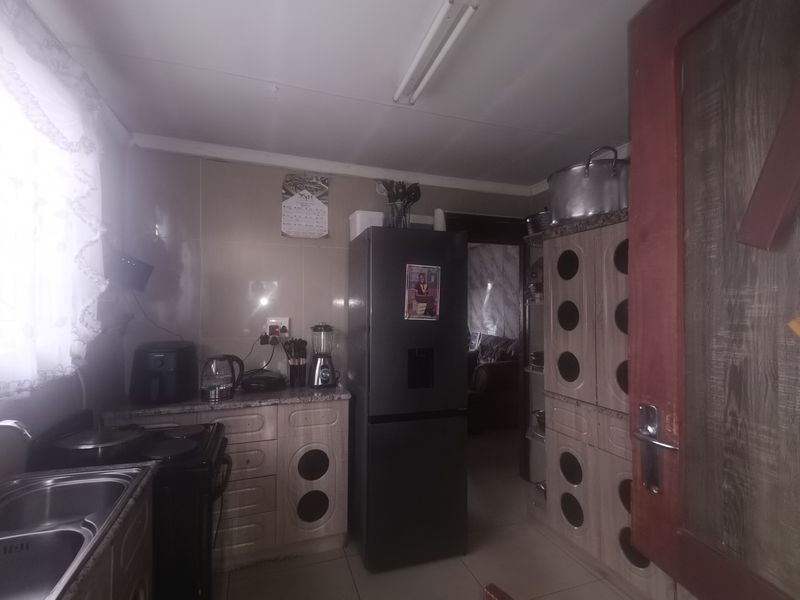 A functional kitchen featuring built-in cabinetry, a double sink, and tiled splashbacks, offering a practical layout for daily meal preparation.