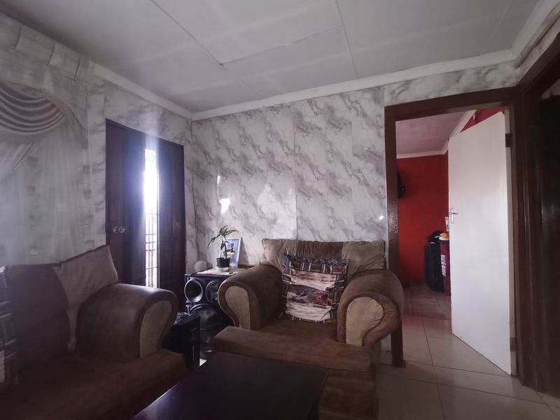 Living room featuring tiled flooring and marble-effect wall paneling, providing a functional space with potential for cosmetic updates.