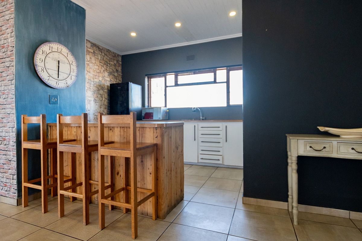 A modern kitchen featuring a wooden breakfast island, white cabinetry, tiled flooring, and a feature wall with stone cladding and blue paint.