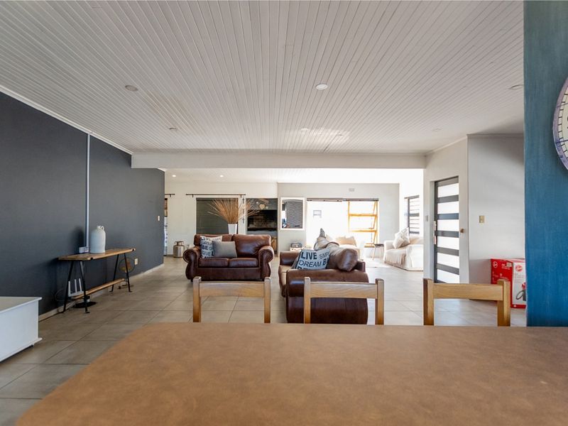 Spacious open-plan living area featuring tiled floors, a tongue and groove ceiling, and a built-in fireplace, creating a comfortable and functional family space.
