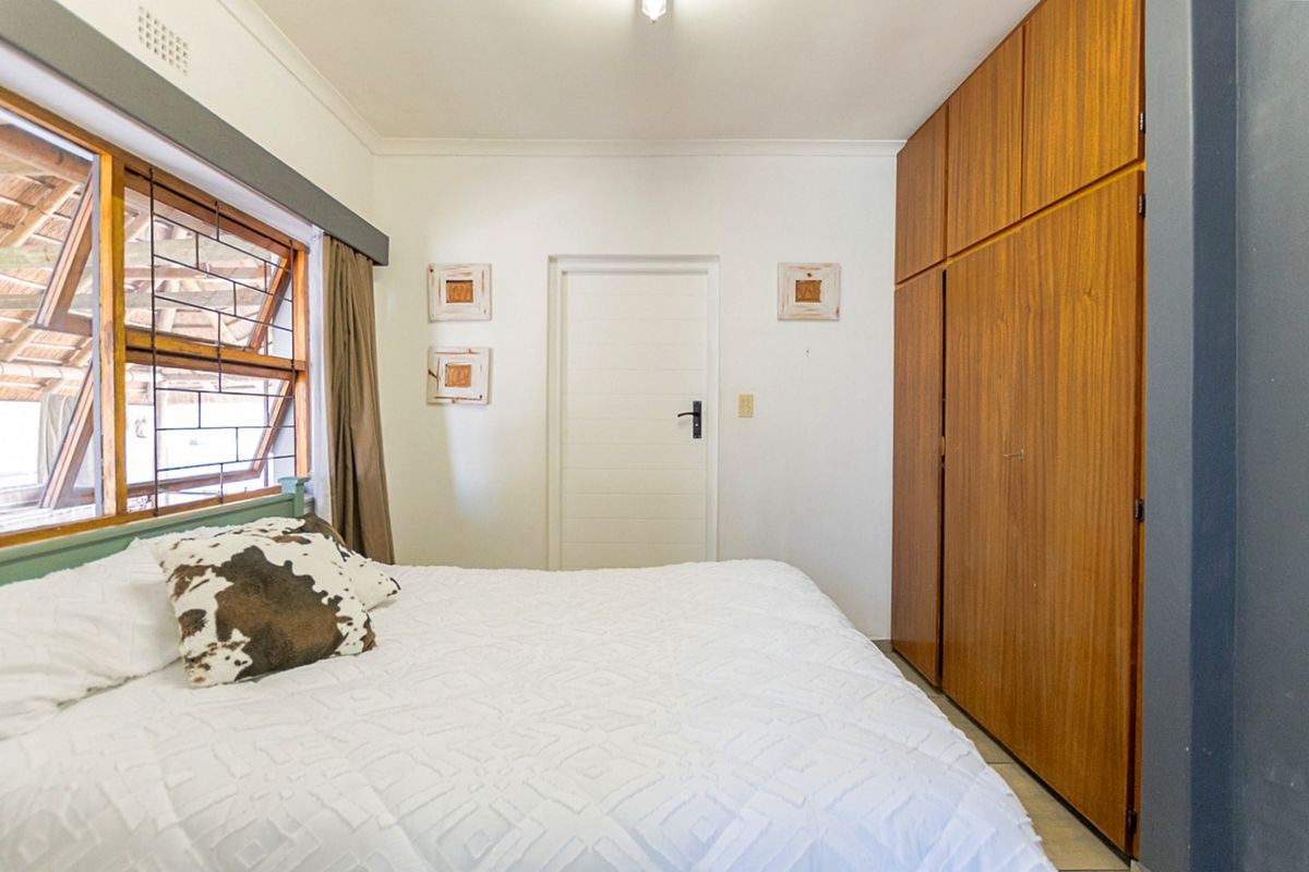 A bedroom featuring built-in wooden cupboards and louvered windows, providing functional storage and natural ventilation.