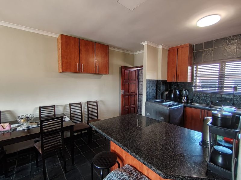 Open-plan kitchen and dining area featuring granite countertops, wooden cabinetry, and slate tile flooring with a functional layout.