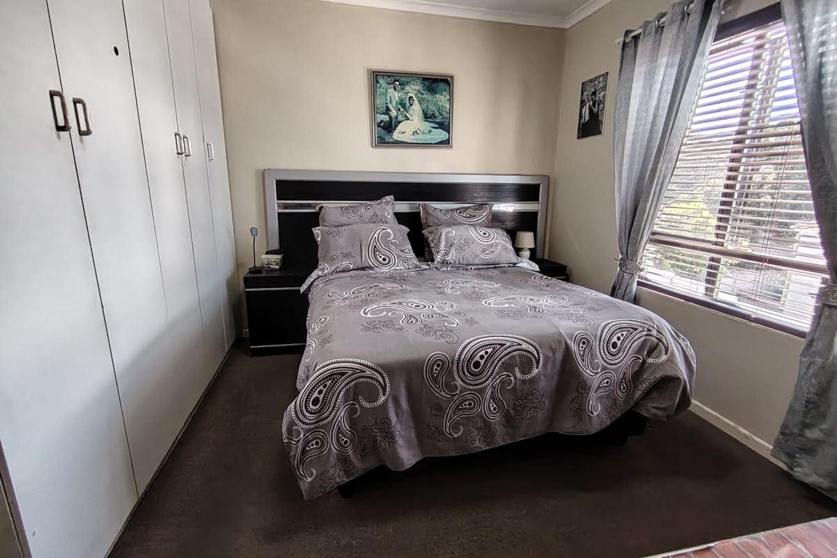 A well-maintained bedroom featuring built-in cupboards, carpeted flooring, and a window with fitted blinds, offering a functional and comfortable living space.