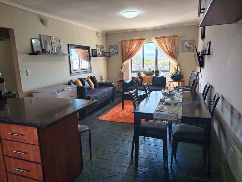 Open-plan living and dining area featuring slate tile flooring, a granite-topped kitchen island, and large windows providing natural light and views.