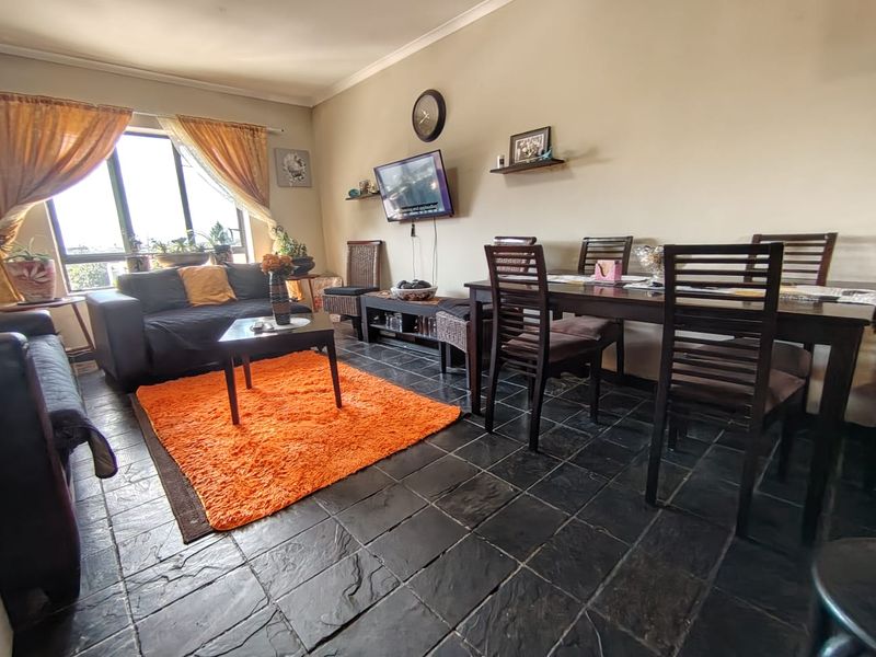 Open plan living and dining area featuring dark slate tile flooring and neutral wall finishes, providing a functional space for relaxation and meals.