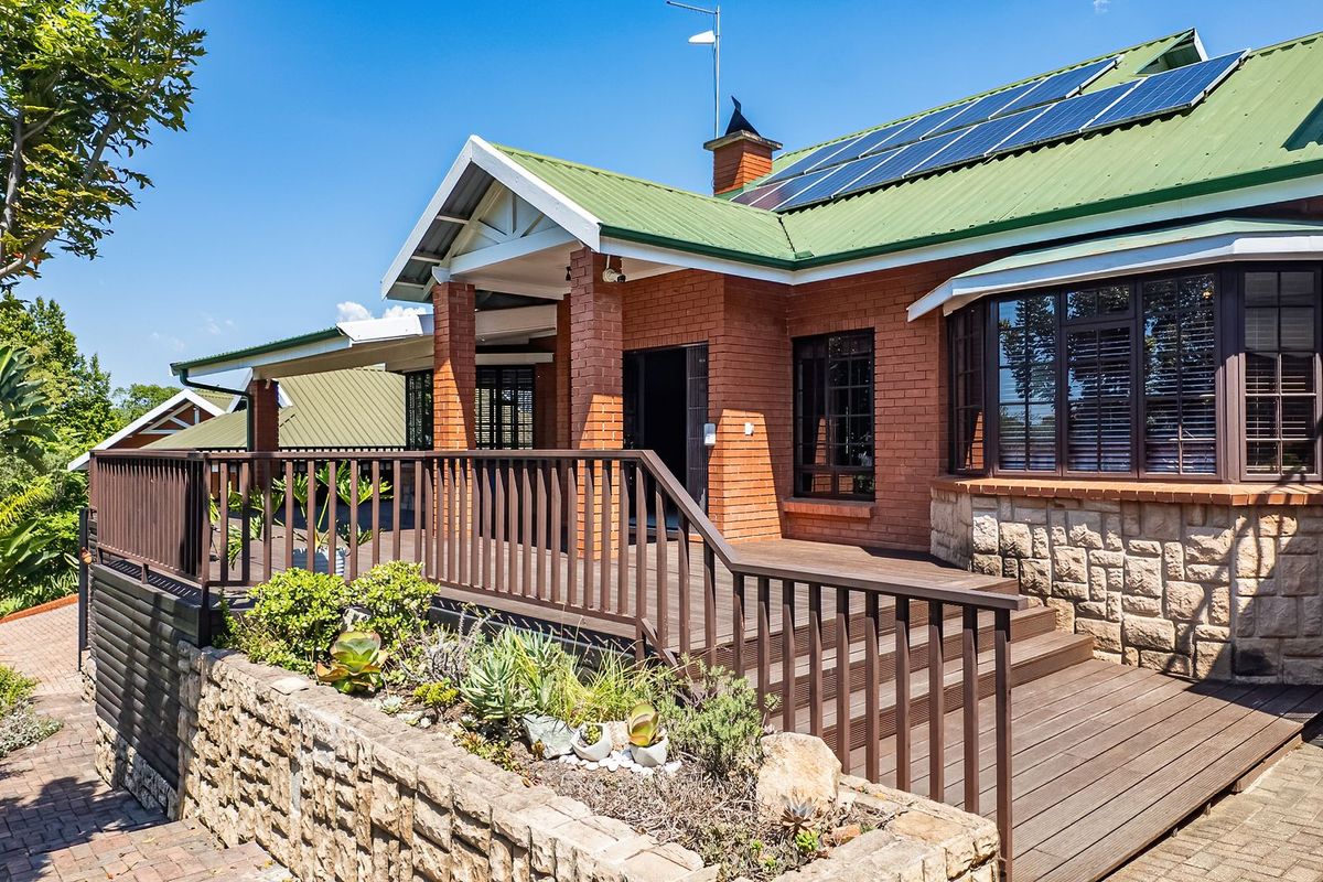 A well-maintained rear exterior featuring a spacious timber deck, stone and brick facade, and integrated solar panels on the roof.