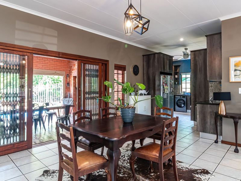 Open plan living and dining area featuring tiled floors, modern pendant lighting, and large sliding doors providing seamless access to the outdoor patio area.