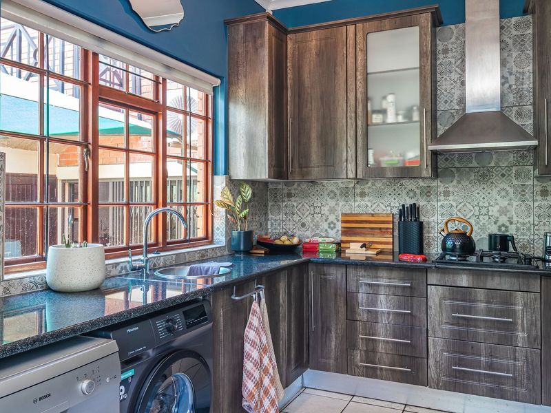 A well-appointed kitchen featuring dark wood cabinetry, granite countertops, a patterned tile backsplash, and integrated stainless steel appliances.
