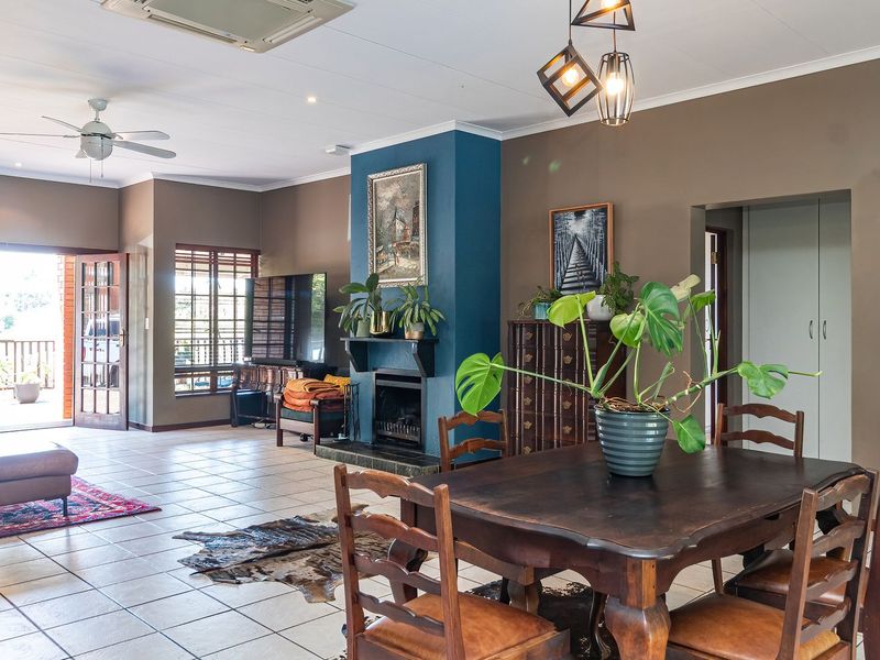Spacious open-plan living and dining area featuring tiled floors, a central fireplace, and direct access to an outdoor patio through french doors.