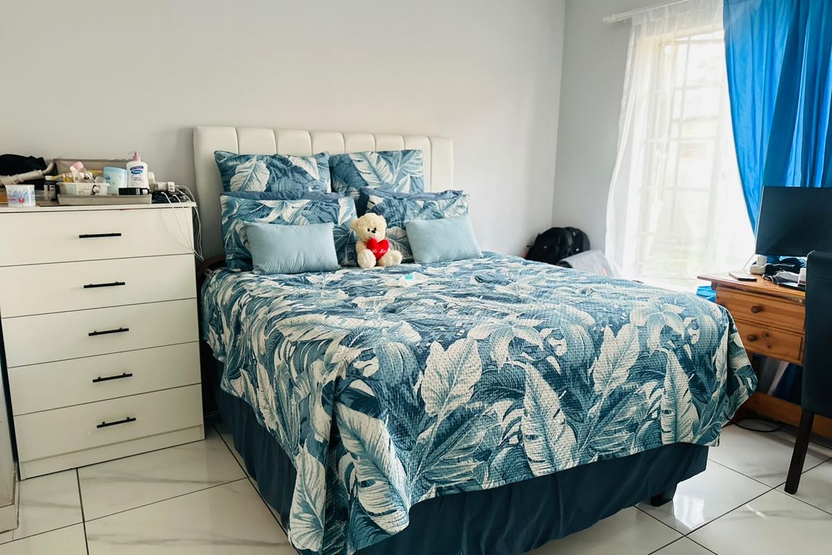 A bedroom featuring tiled flooring and a window with a curtain rod, providing a functional and well-lit living space.