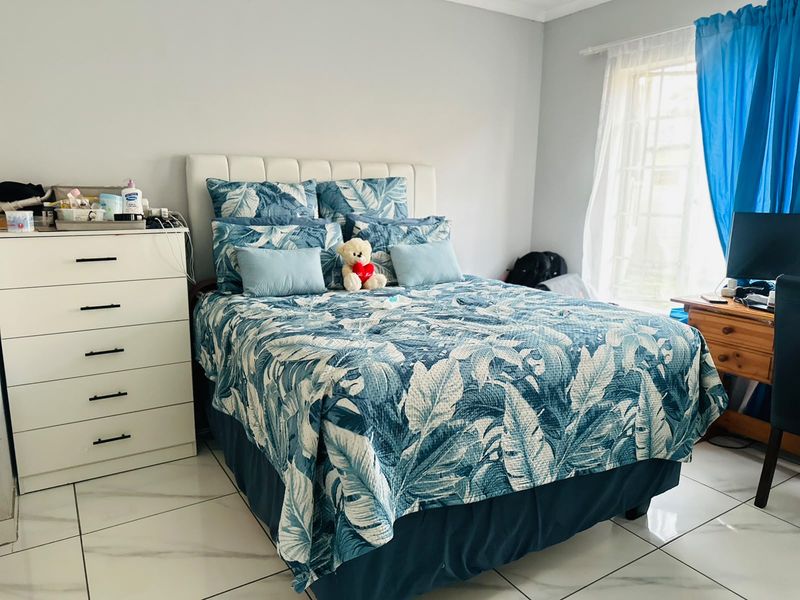 A bedroom featuring tiled flooring and a window with a curtain rod, providing a functional and well-lit living space.
