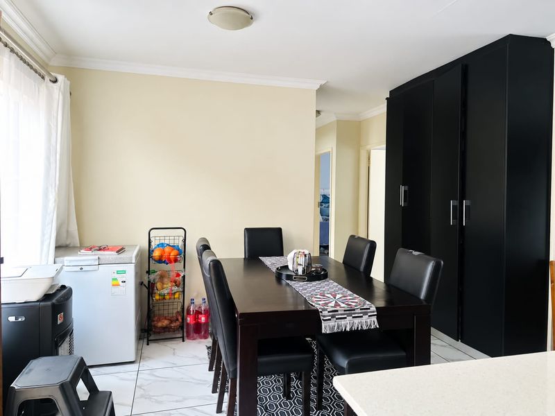 A well-maintained dining area featuring modern black built-in cabinetry, neutral wall tones, and clean tiled flooring, providing a functional space for meals.