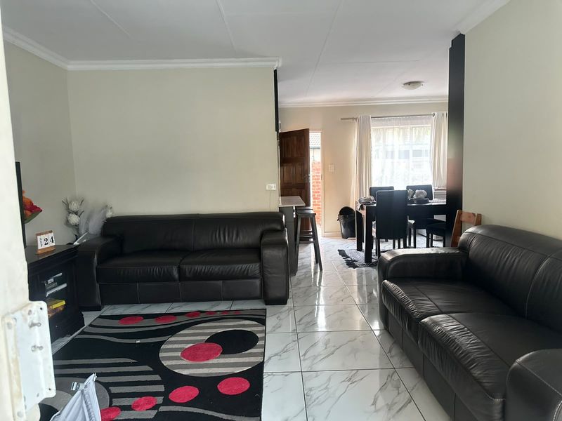 Open-plan living and dining area featuring marble-look floor tiles and a breakfast bar, creating a connected space for daily living.