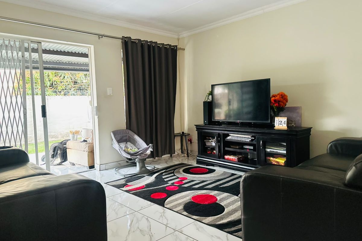 A living room featuring tiled flooring and a sliding glass door providing access to an outdoor patio area.