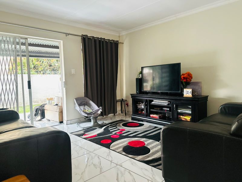 A living room featuring tiled flooring and a sliding glass door providing access to an outdoor patio area.