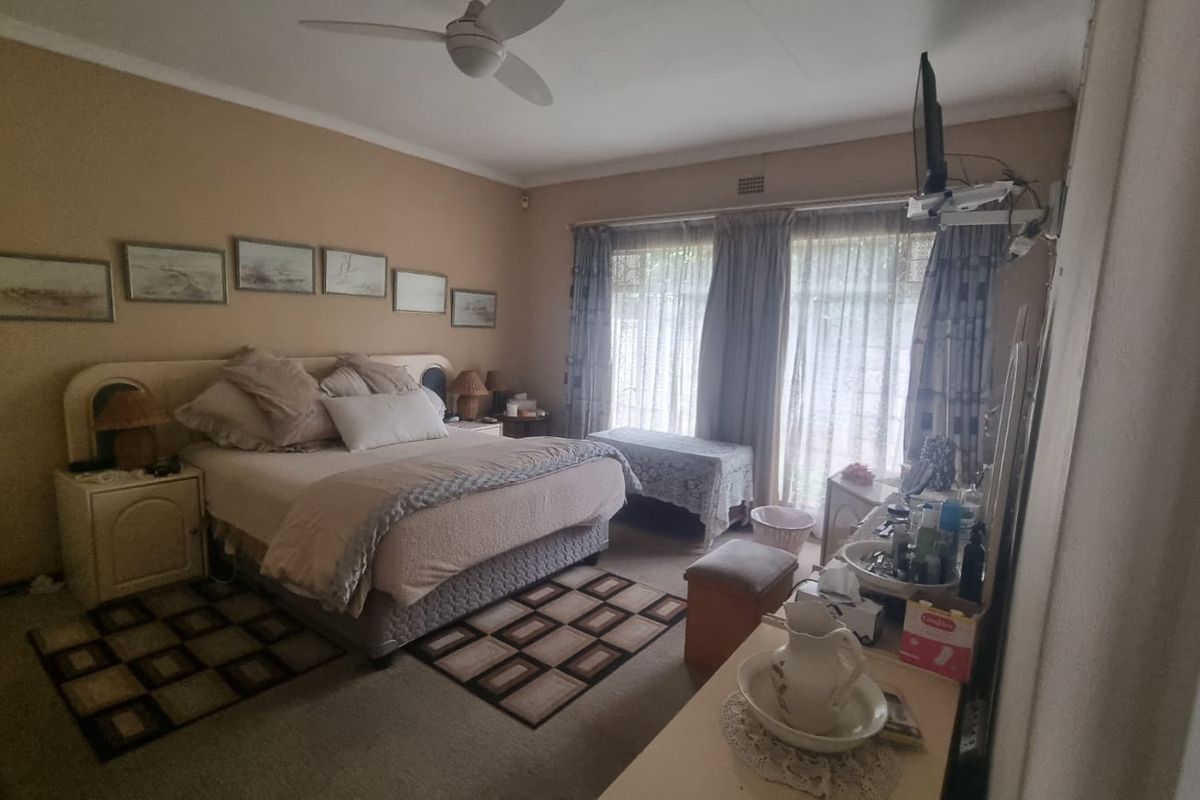 A spacious bedroom featuring carpeted flooring, a ceiling fan, and large sliding glass doors that provide natural light.