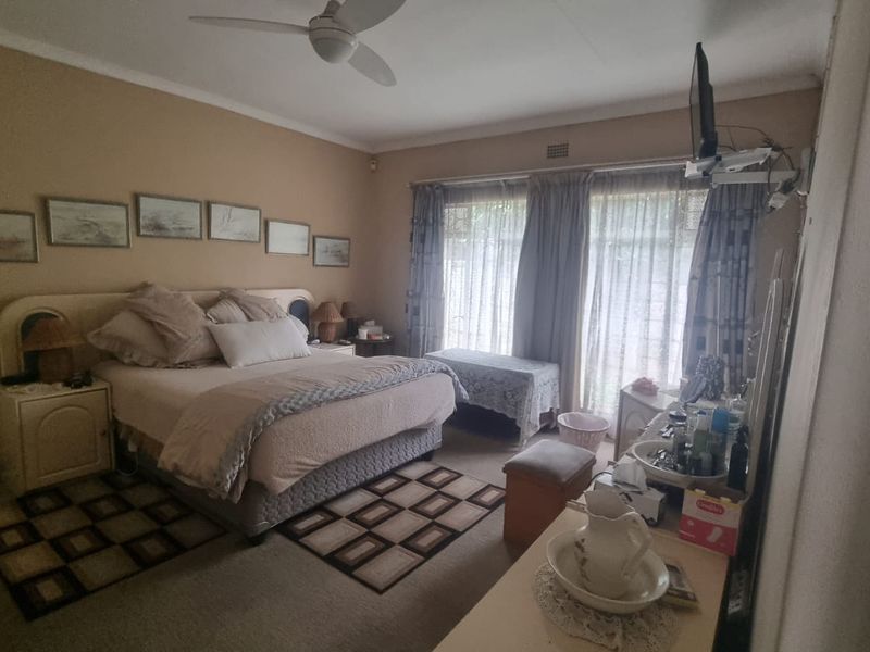 A spacious bedroom featuring carpeted flooring, a ceiling fan, and large sliding glass doors that provide natural light.