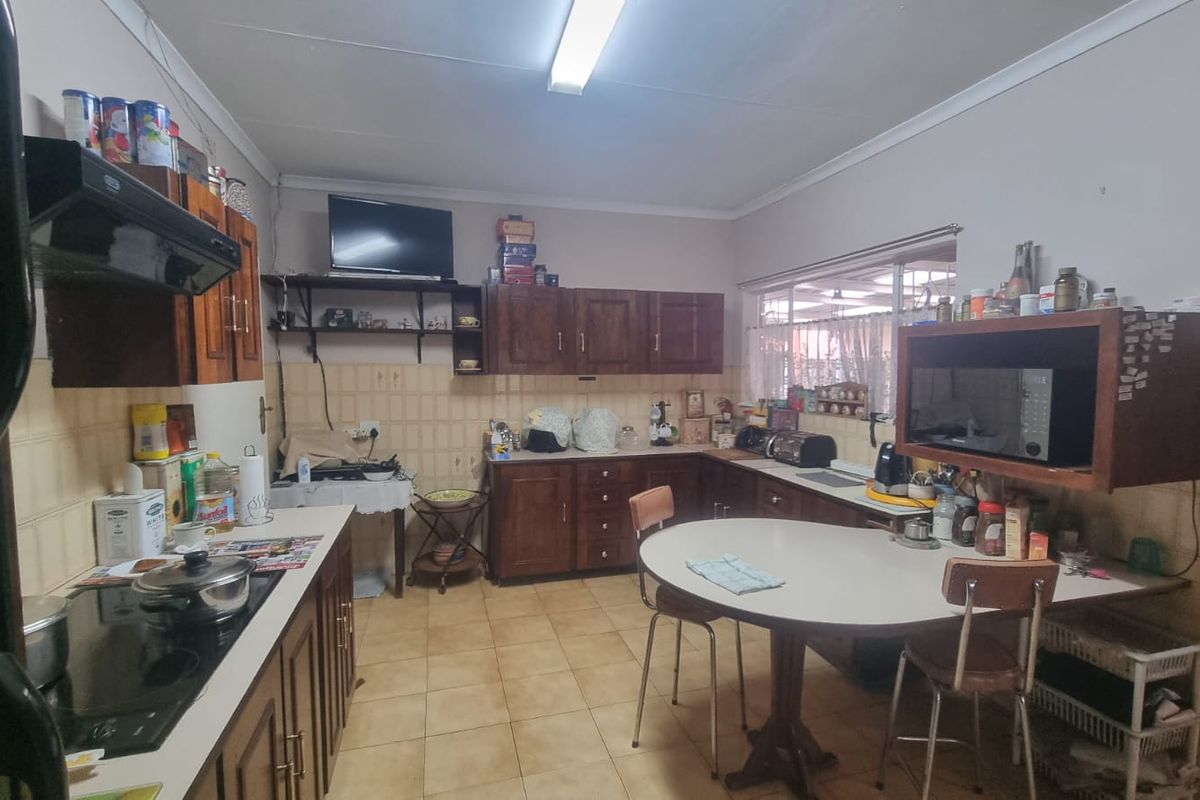 A dated kitchen featuring wooden cabinetry, ceramic tile flooring, and a tiled backsplash, offering a functional layout with potential for modern renovation.