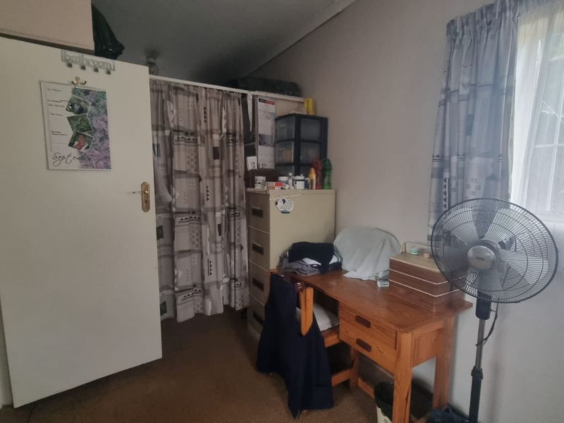 A bedroom featuring a built-in cupboard and a window with security bars, requiring cosmetic updates to improve its overall condition and appeal.