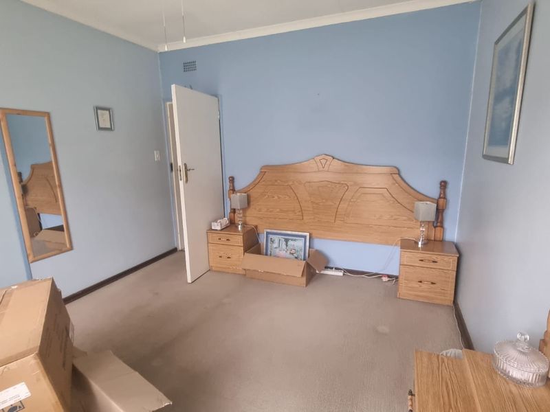 A bedroom featuring blue walls, carpeted flooring, and a built-in cupboard, currently in need of cosmetic updates and refreshing.