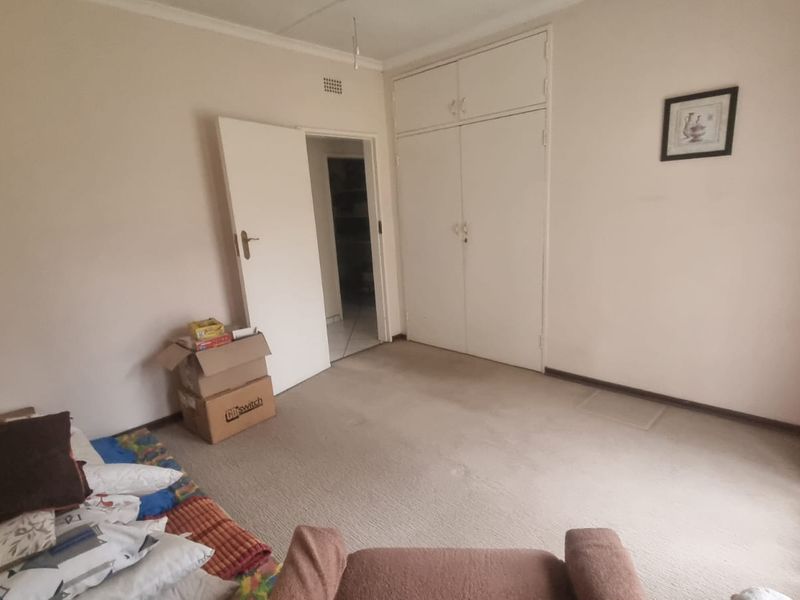 A bedroom featuring neutral walls, carpeted flooring, and built-in storage cupboards.