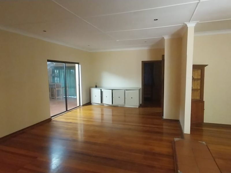 Spacious living area featuring polished hardwood flooring, recessed lighting, and a sliding glass door providing access to the outdoor patio.