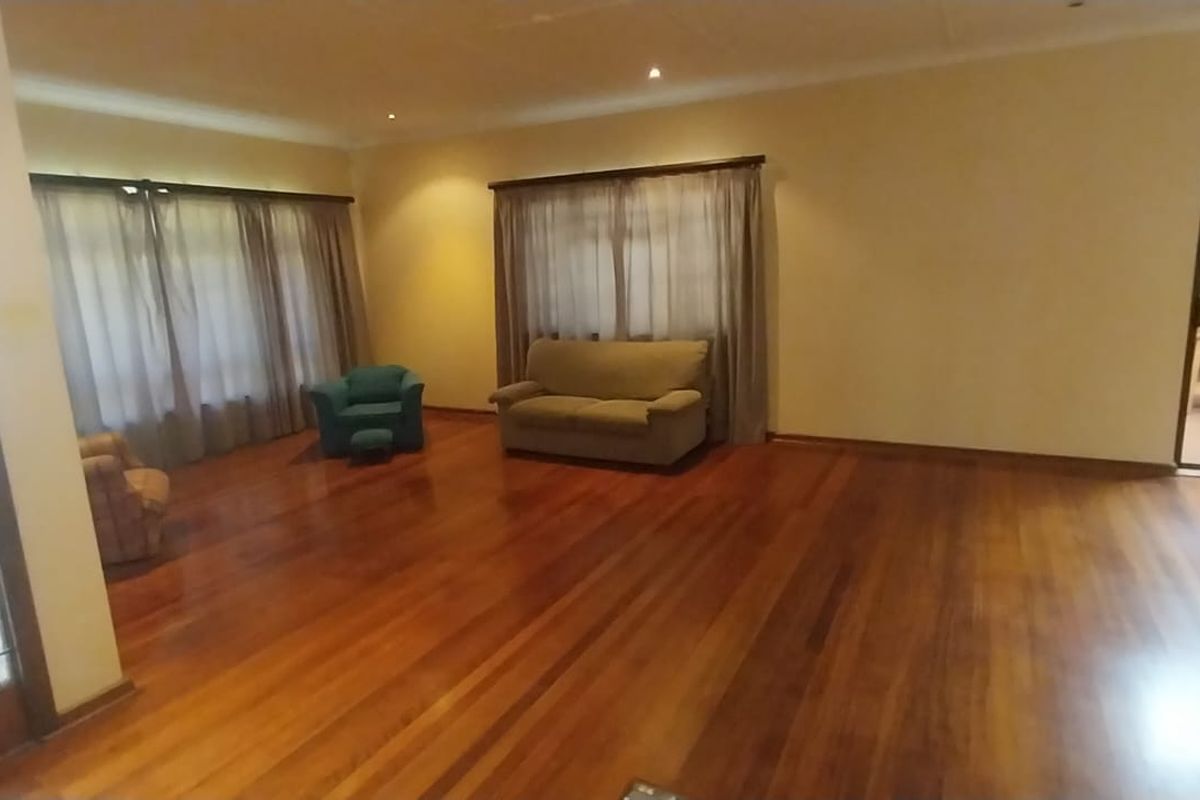 Spacious living area featuring polished hardwood flooring, recessed lighting, and large windows with access to an outdoor patio area.