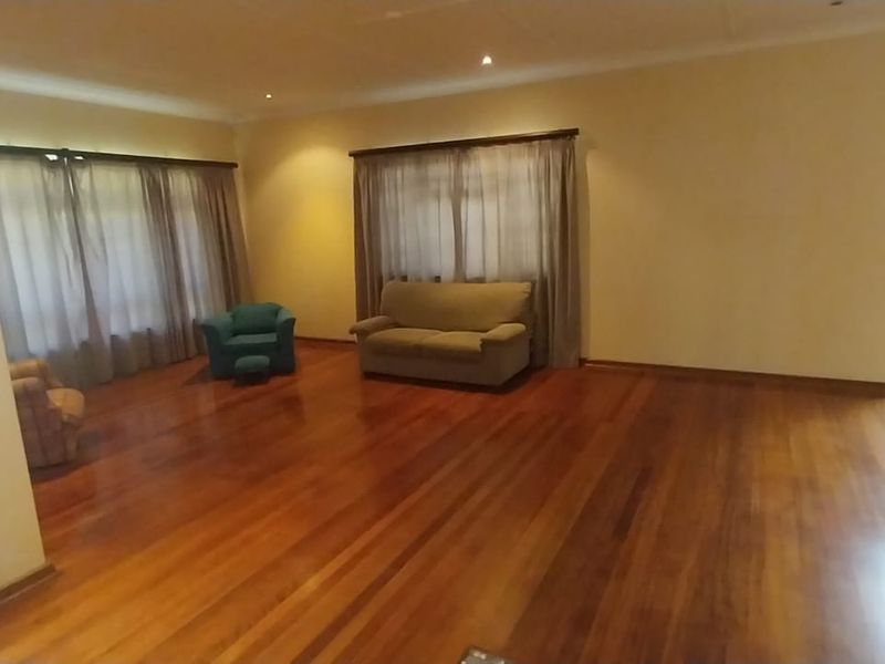 Spacious living area featuring polished hardwood flooring, recessed lighting, and large windows with access to an outdoor patio area.
