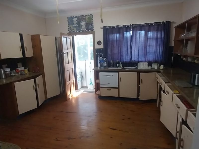 A dated kitchen featuring timber flooring, built-in cabinetry, and laminate countertops, offering significant potential for a modern renovation.
