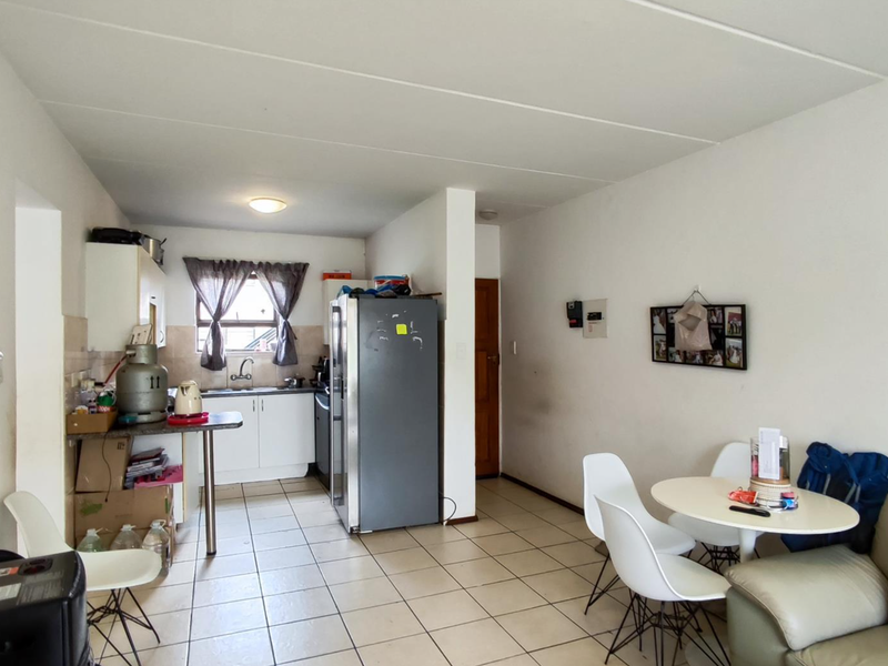 Open plan living and kitchen area featuring tiled flooring, functional cabinetry, and a tiled backsplash, offering a practical layout for daily living.