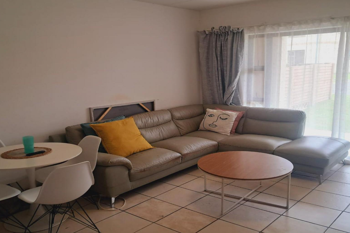 A living room area featuring tiled flooring and a sliding glass door providing access to the exterior.