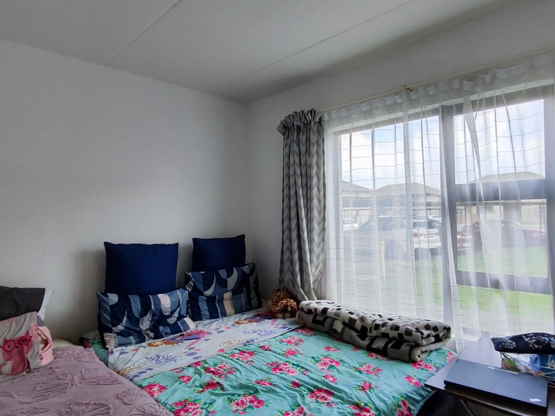 A bedroom featuring a large window with natural light, providing a view of the exterior parking area.