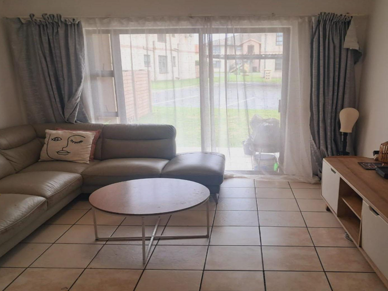 A living room featuring ceramic floor tiles and a large sliding glass door providing access to the exterior.