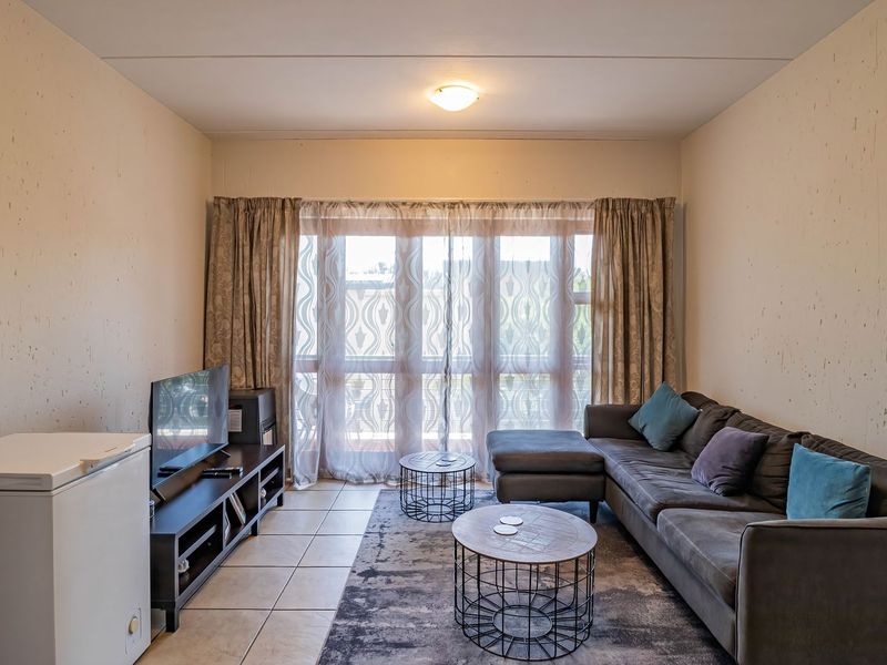 A living room featuring tiled flooring, textured walls, and a large sliding glass door providing natural light.