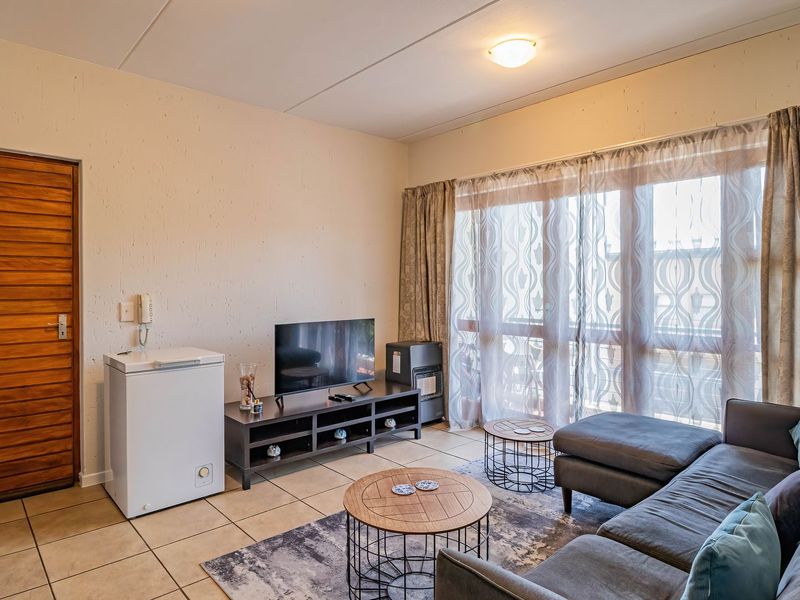 A living room featuring tiled flooring, an intercom system, and a large sliding glass door that provides natural light and access to the exterior.