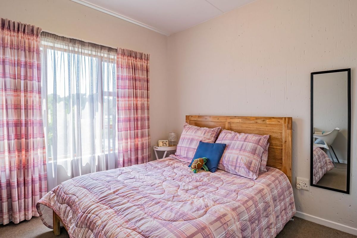 A standard bedroom featuring a large window with curtains and neutral wall finishes.