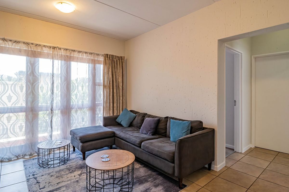 A living room featuring tiled flooring and a large sliding glass door that provides access to the outdoor area.