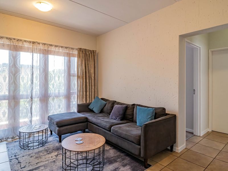 A living room featuring tiled flooring and a large sliding glass door that provides access to the outdoor area.