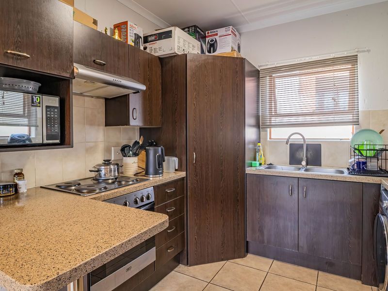 Functional kitchen featuring dark wood cabinetry, laminate countertops, integrated oven and hob, and dedicated space for a washing machine.